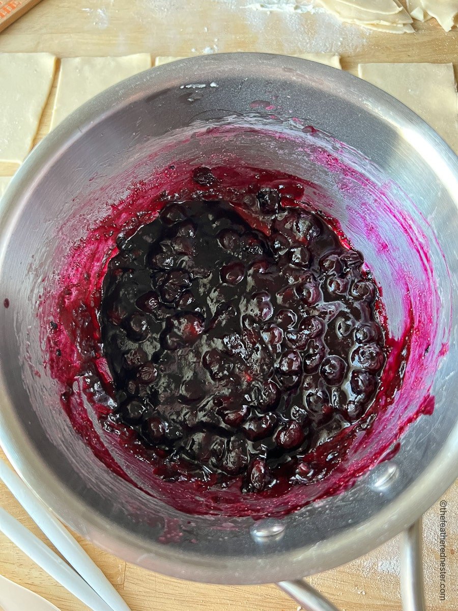 A saucepan of cooked blueberry hand pie filling.