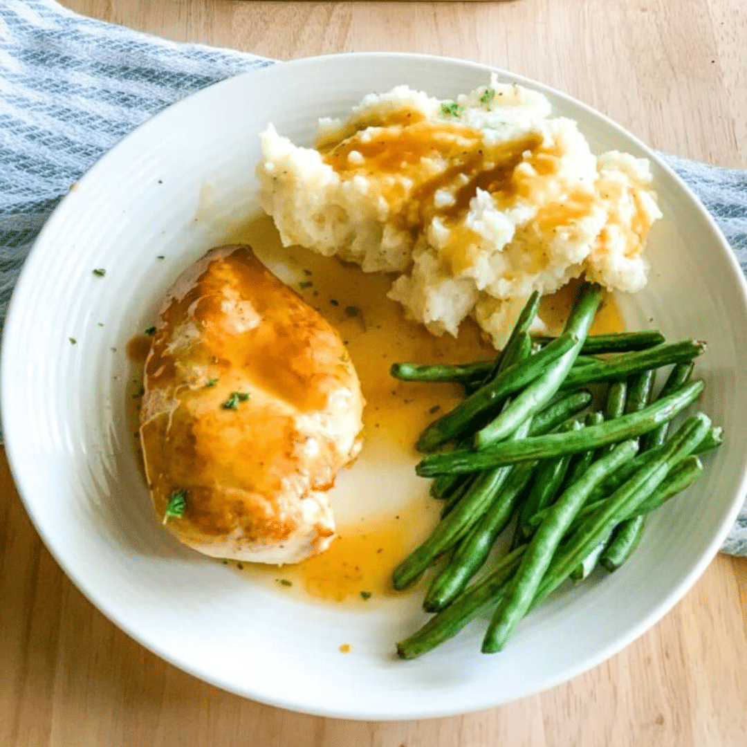 Dinner plate of cooked poultry, mashed potatoes and green beans.