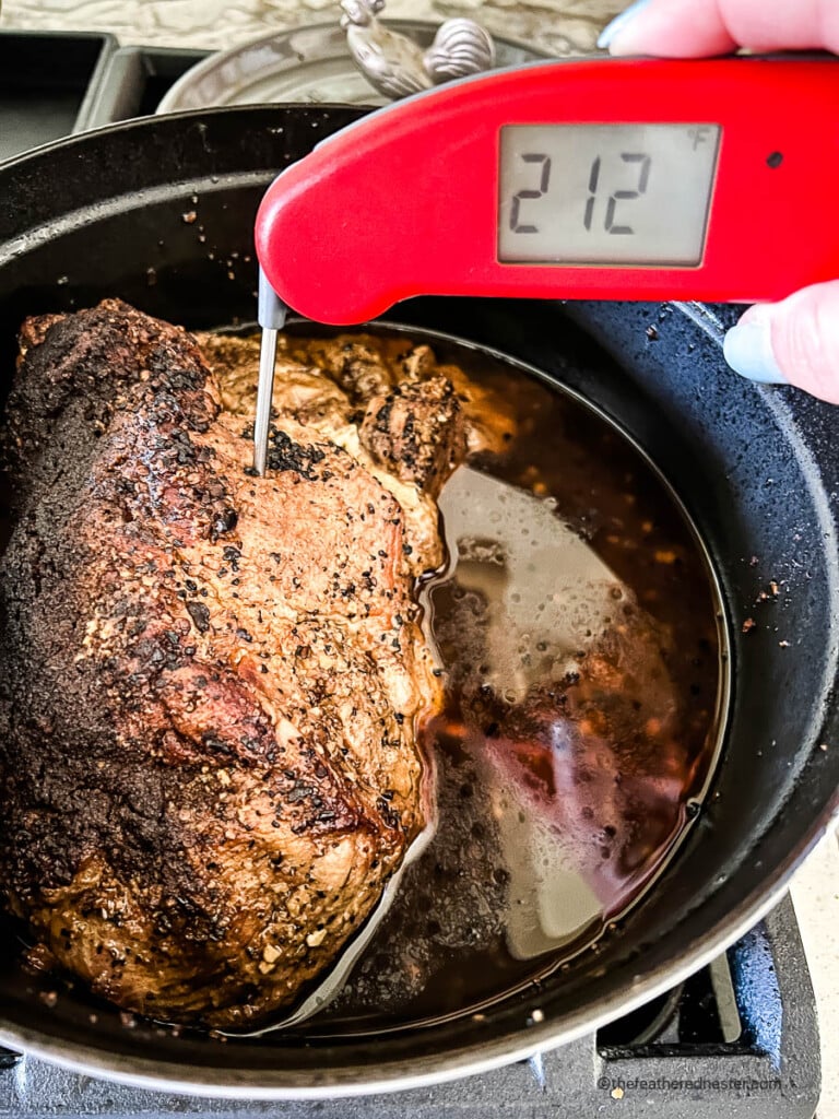 Digital food thermometer measuring internal temperature of pork shoulder roast.