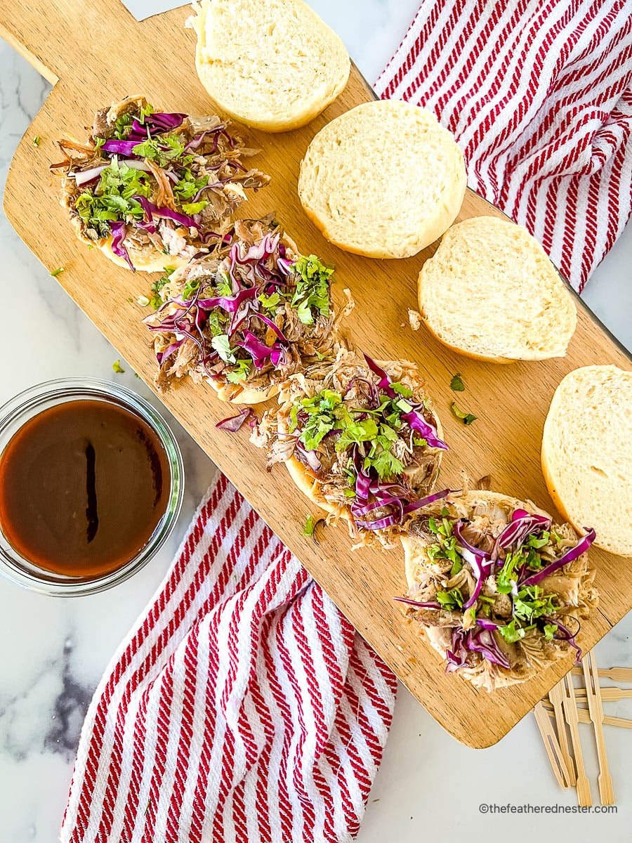 Overhead: 4 open faced buns topped with shredded meat and red cabbage slaw.