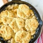 Homemade fruit cobbler with biscuit topping in a cast iron skillet.