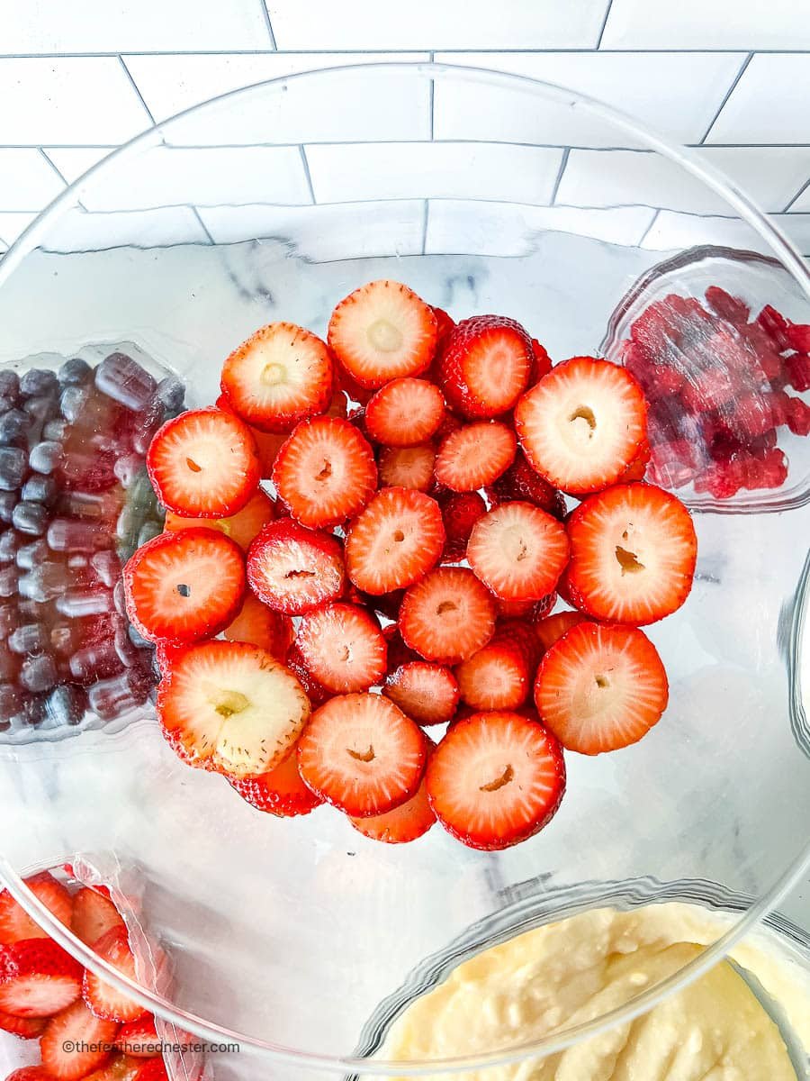 overhead: slices of fresh strawberries in a clear glass bowl.
