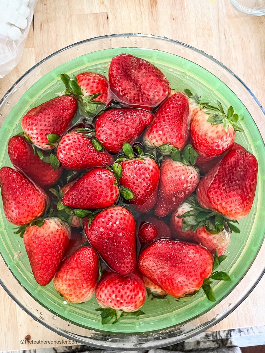 Whole fresh strawberries in a bowl of water.