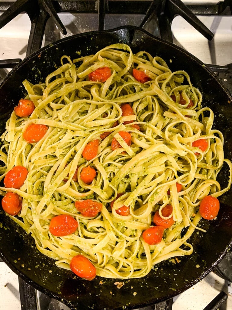 noodles and tomatoes cooking in a skillet.