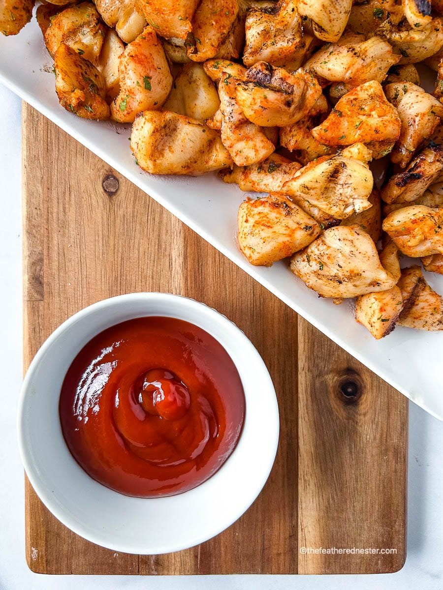 Chick Fil A chicken nuggets on a white plate above a small bowl with ketchup.