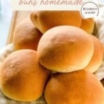 A vertical image with the title "HAMBURGER buns homemade" at the top. The image is a close-up of a pile of freshly baked, golden-brown hamburger buns resting on a checkered napkin. The website "TheFeatheredNester.com" is at the bottom.