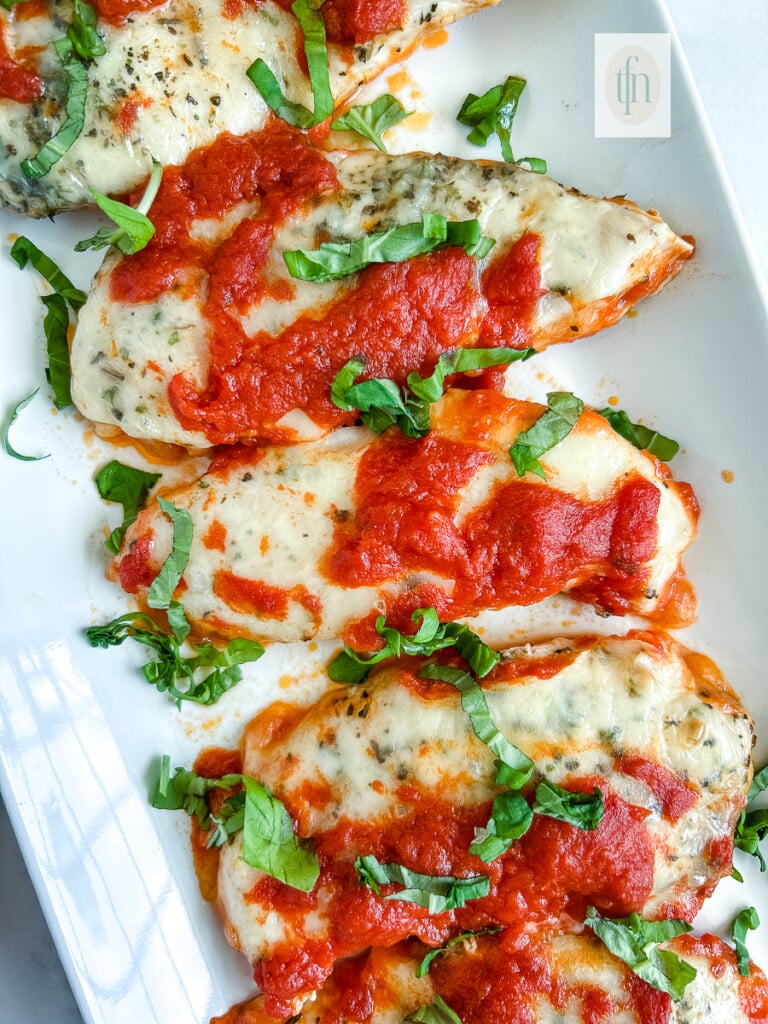 Italian baked chicken cutlets, close up on a white plate.