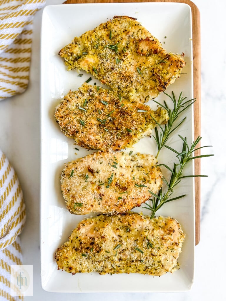 Four pieces of panko breaded chicken on a white serving plate.