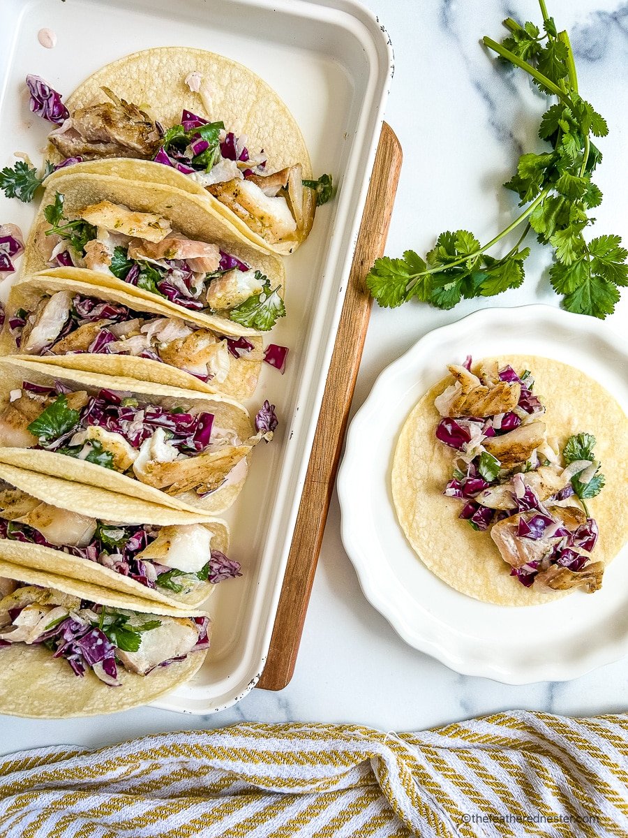 Platter full of pan seared rockfish tacos topped with fish taco slaw.