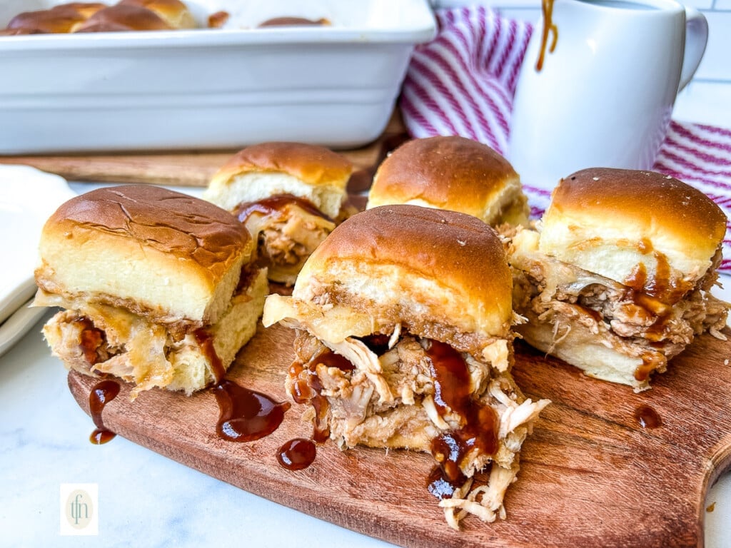 Wood platter full of BBQ chicken sliders.