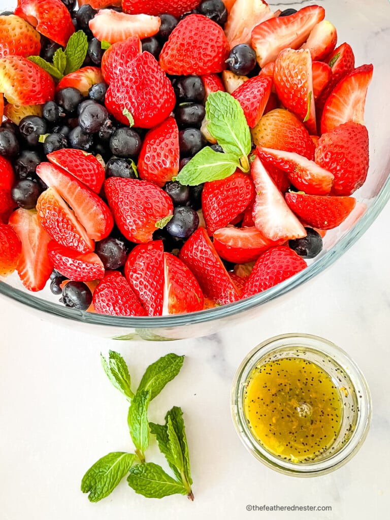 Bowl of mixed berry salad next to a small bowl of citrus poppy seed dressing.