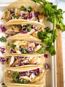 Platter of rockfish tacos topped with cucumber slaw.