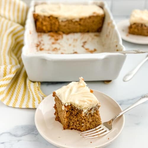 Plated slice of apple cake with pan behind it.