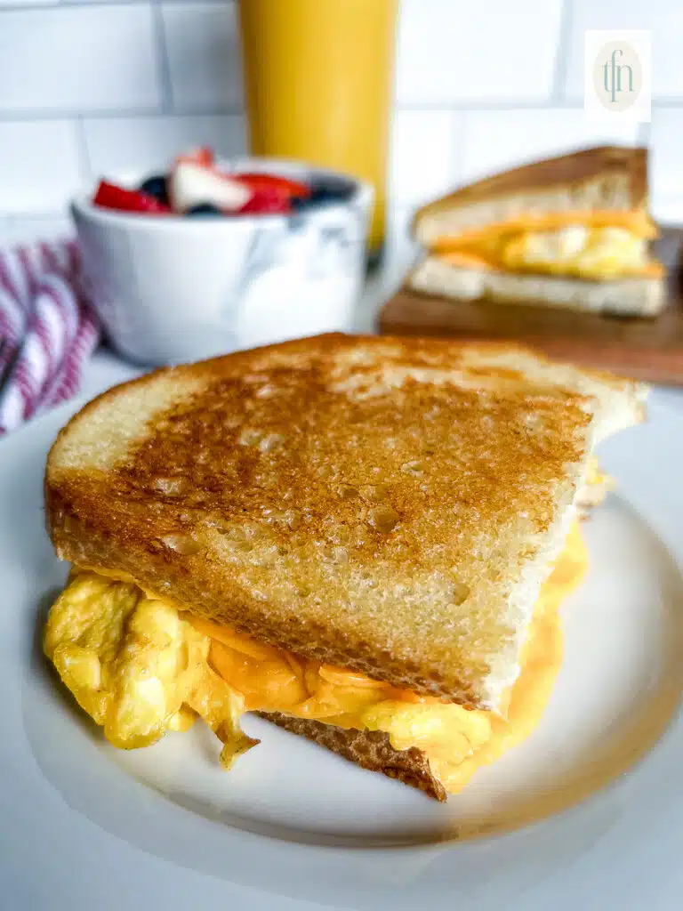 Perfectly toasted sourdough breakfast sandwich on a white plate.