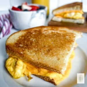 One half of a sourdough breakfast sandwich on a small plate.