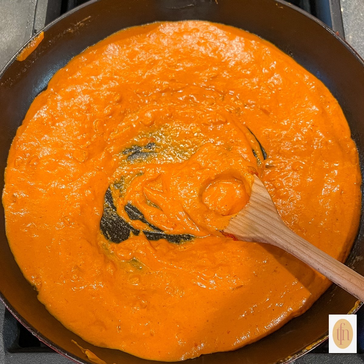 Wooden spoon in a saucepan of creamy vodka sauce.