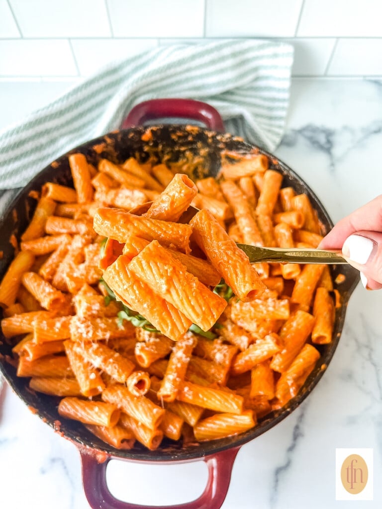 Serving spoon of Carbone spicy rigatoni vodka held above a pan holding the rest of the dish.