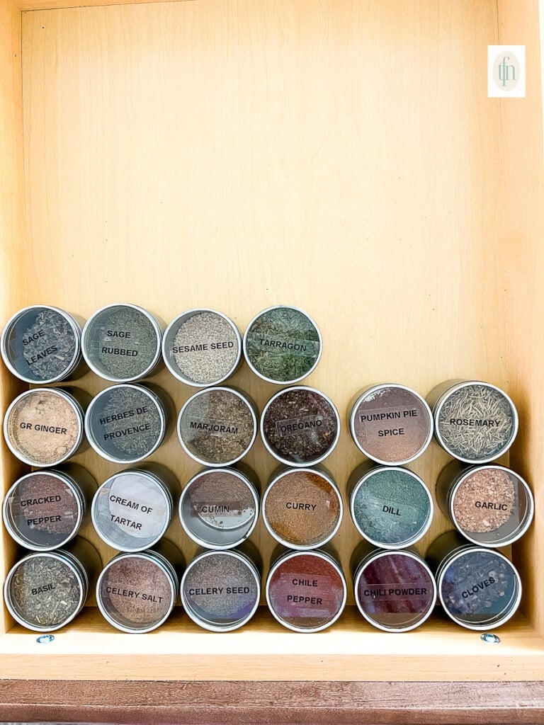 Decluttered and organized spice drawer filled with labeled canisters of dried spices and seasonings.