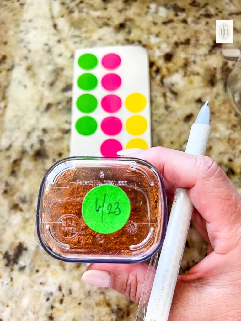 Small green sticker with expiration date for pantry spices written on it.
