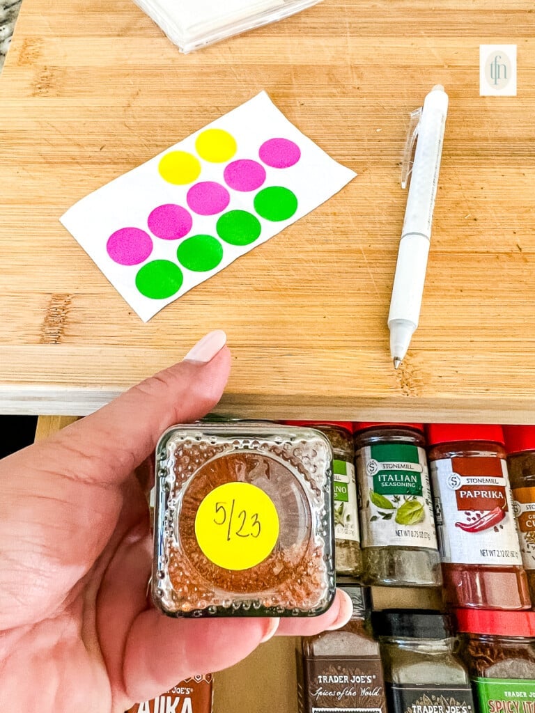 Decluttering and organizing a spice drawer with labeled containers.