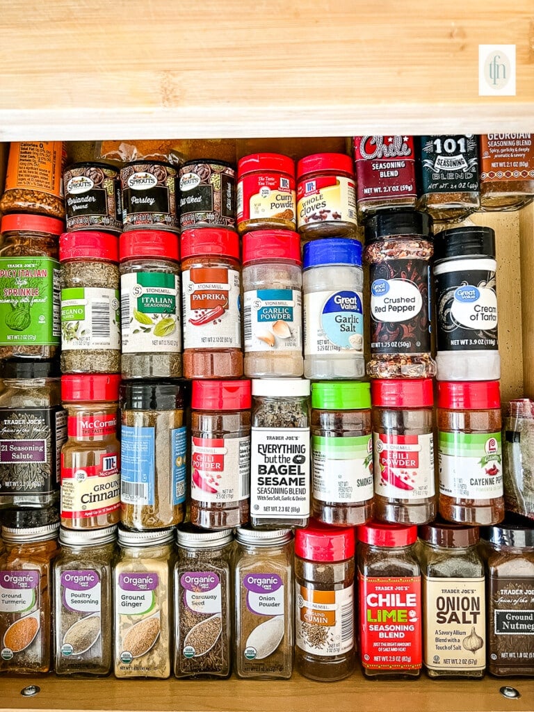 Old bottles of expired spices in a spice cabinet.