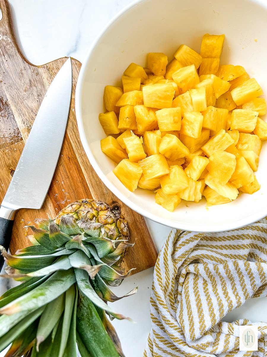 A white bowl full of pineapple chunks.