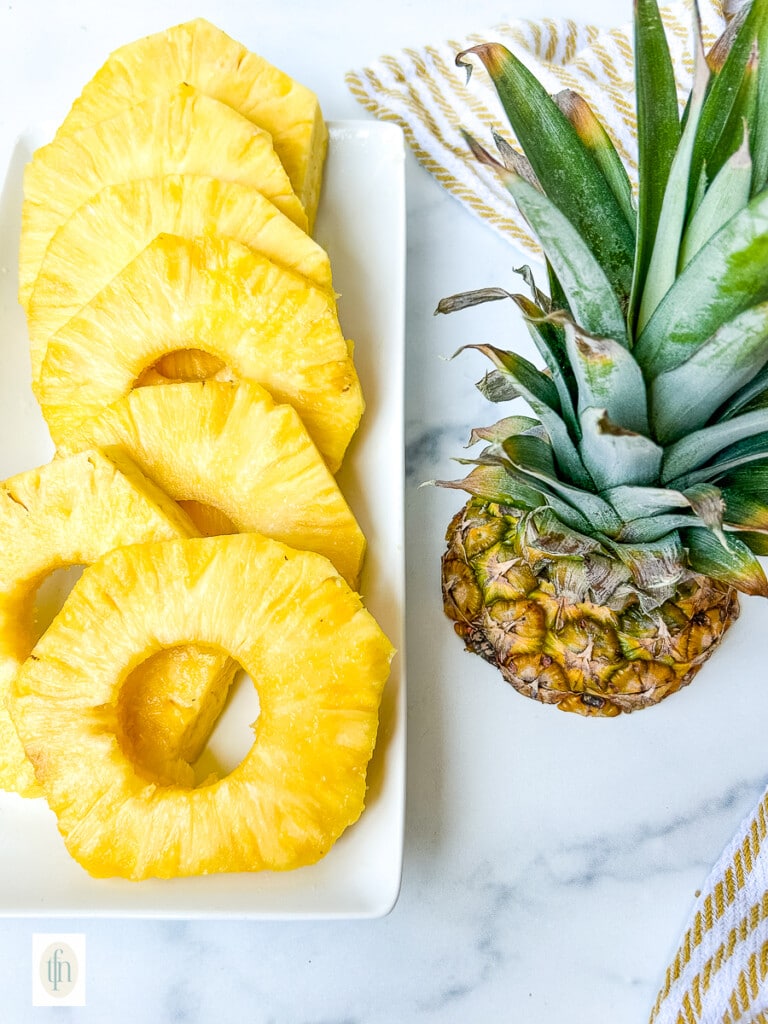 Fresh rings of tropical fruit on a white serving platter.