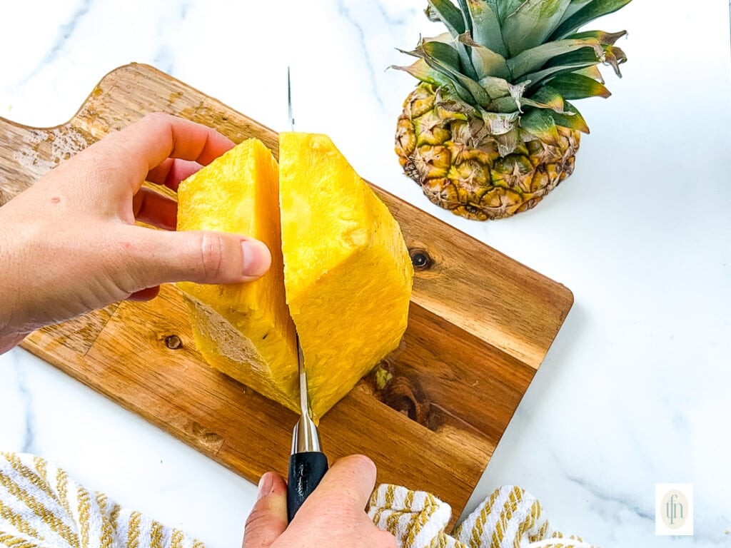 Cutting a whole pineapple after removing the peel.
