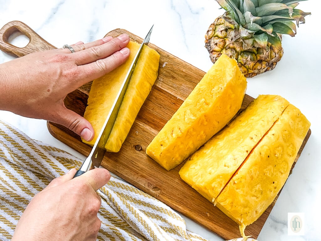 Using a large kitchen knife to core a pineapple.