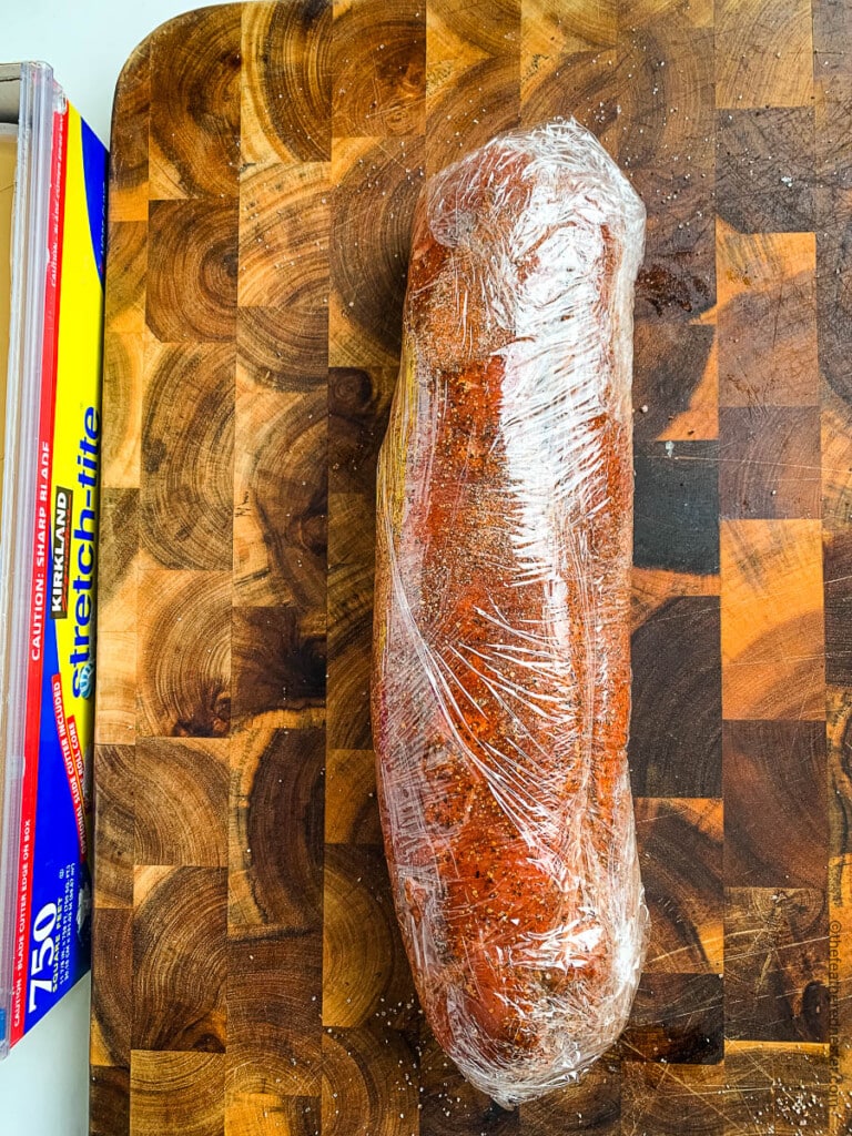 Large piece of seasoned boneless meat wrapped in plastic wrap.