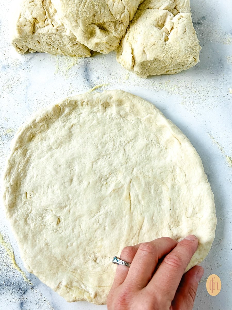 Woman's hand shaping pizza dough sourdough discard.