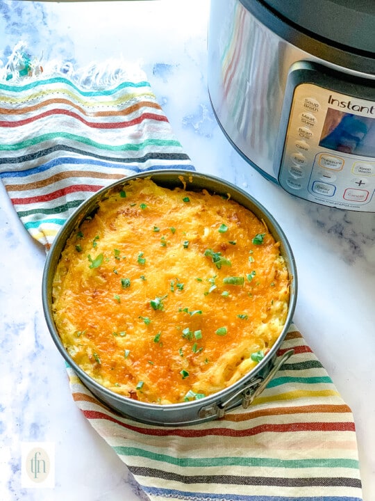 Instant Pot hash brown casserole in a springform pan sitting next to an electric pressure cooker.