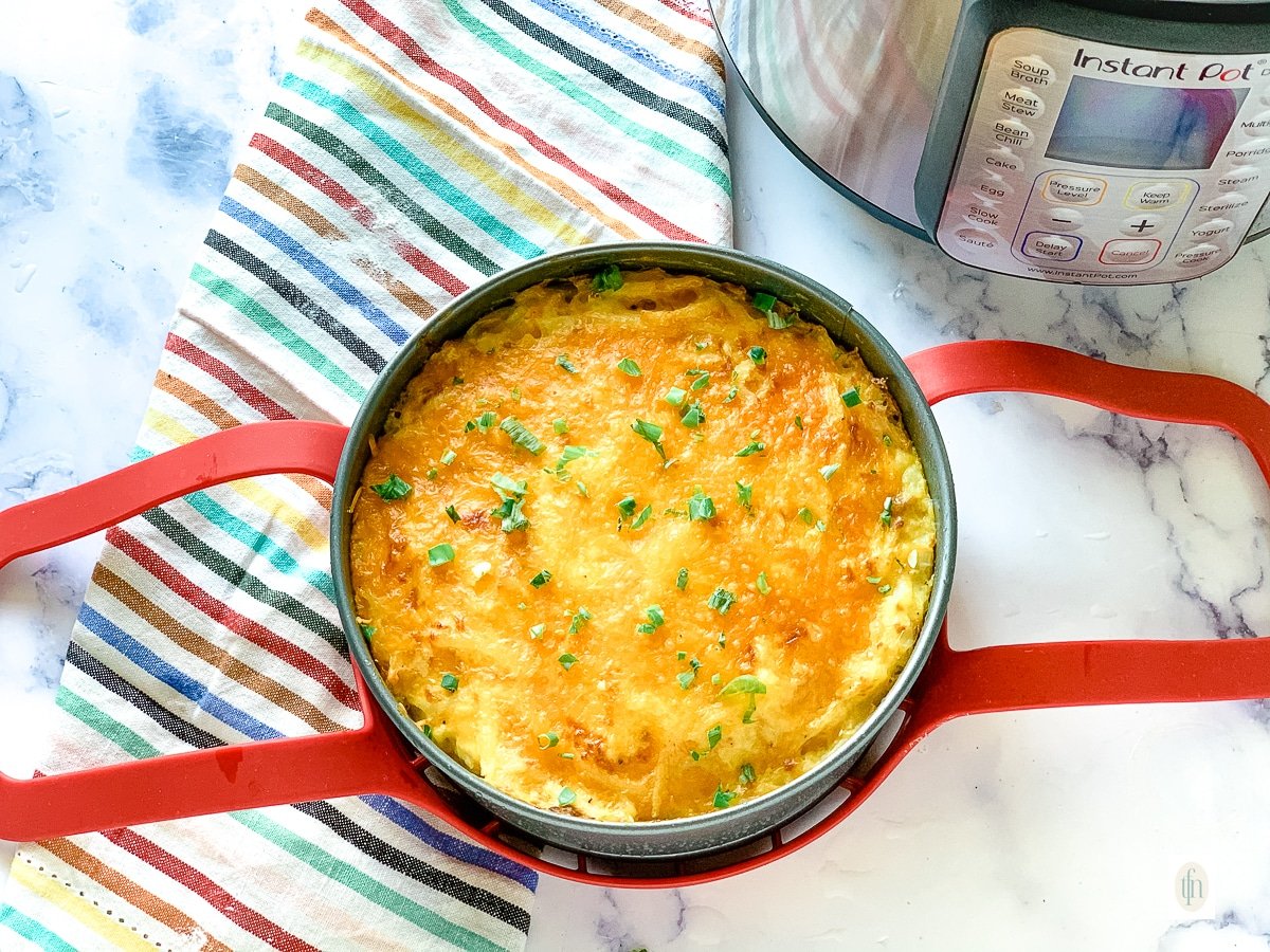 Fully baked Instant Pot hash brown casserole topped with melted cheddar cheese.