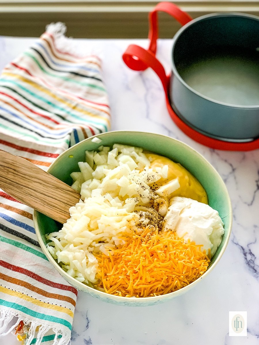 Combining ingredients in a bowl for Instant Pot cheesy potatoes.