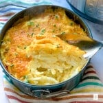 Spoonful of Instant Pot cheesy potatoes above the remaining casserole.