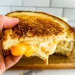 One half of a perfectly cooked sourdough grilled cheese with three cheeses.