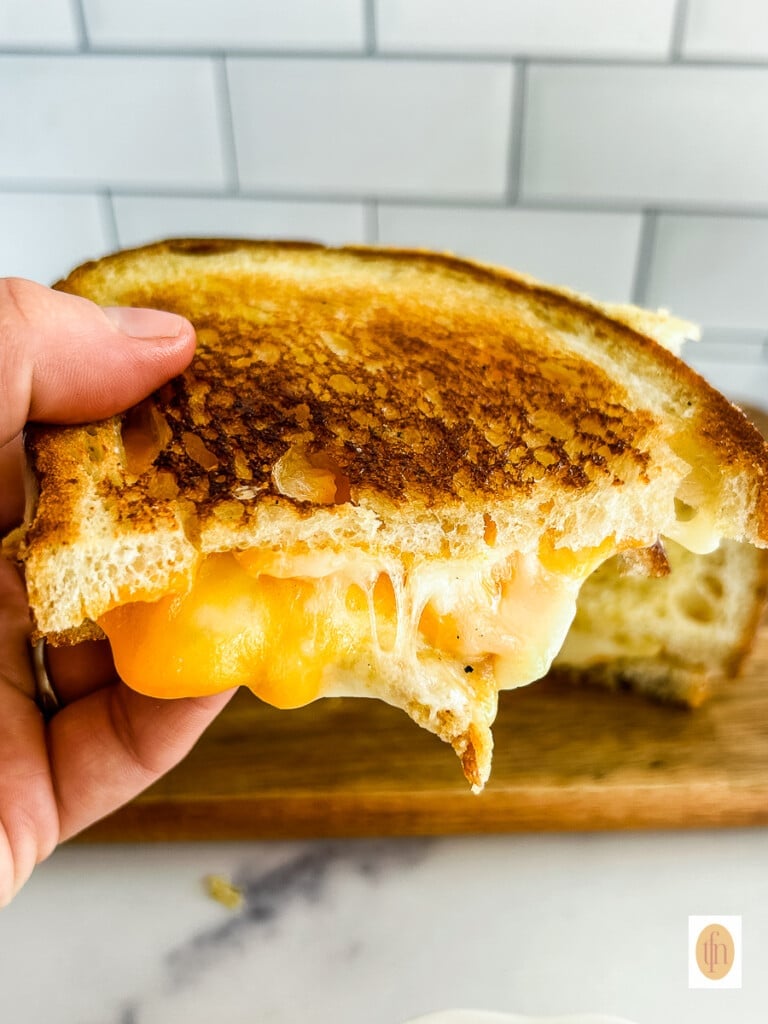 One half of a perfectly cooked sourdough grilled cheese with three cheeses.