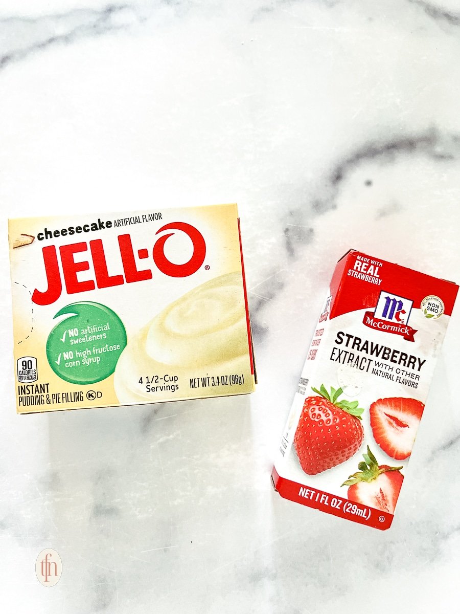 Package of cheesecake flavored Jello instant pudding mix next to a bottle of strawberry extract for strawberry cookie recipe.