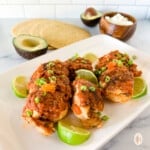 Instant Pot Mexican chicken with limes and scallions on a large white plate.