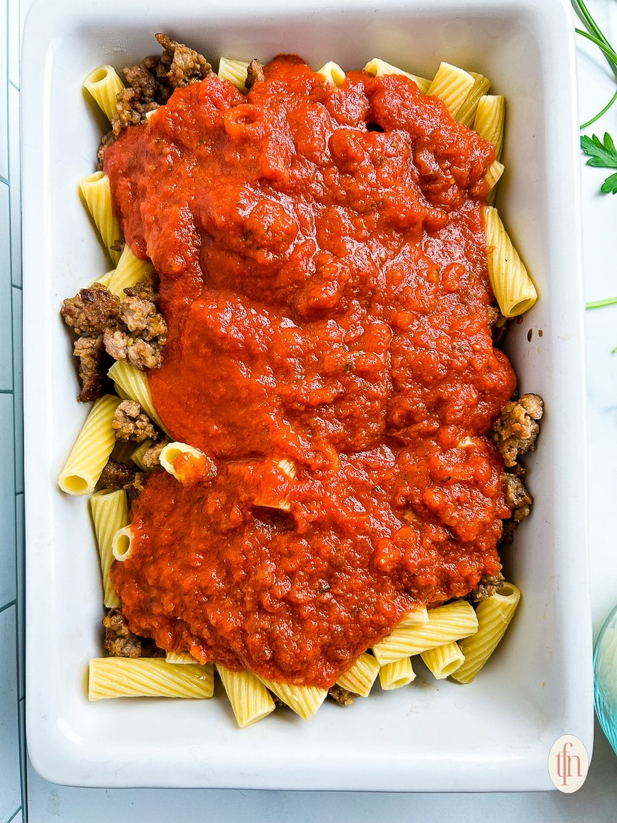 Assembling a sausage rigatoni casserole.