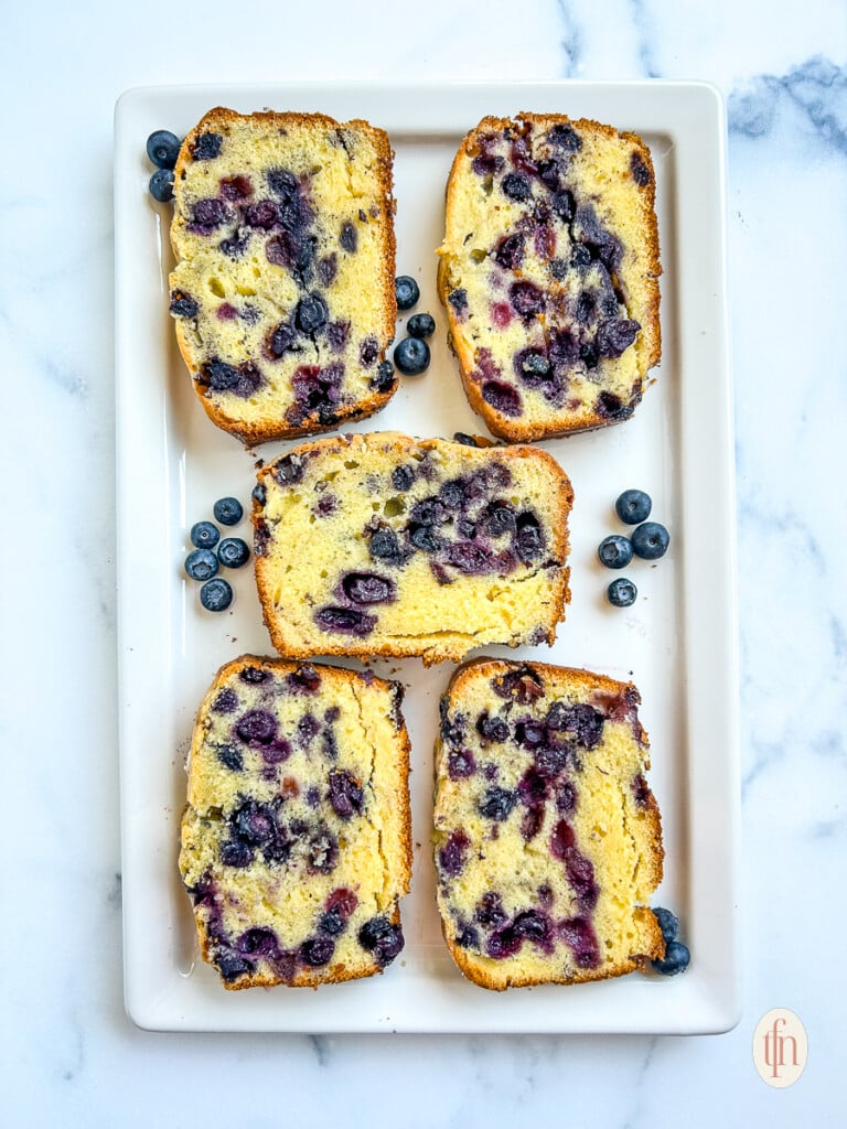 5 slices of blueberry pound cake on a rectangular white serving platter.