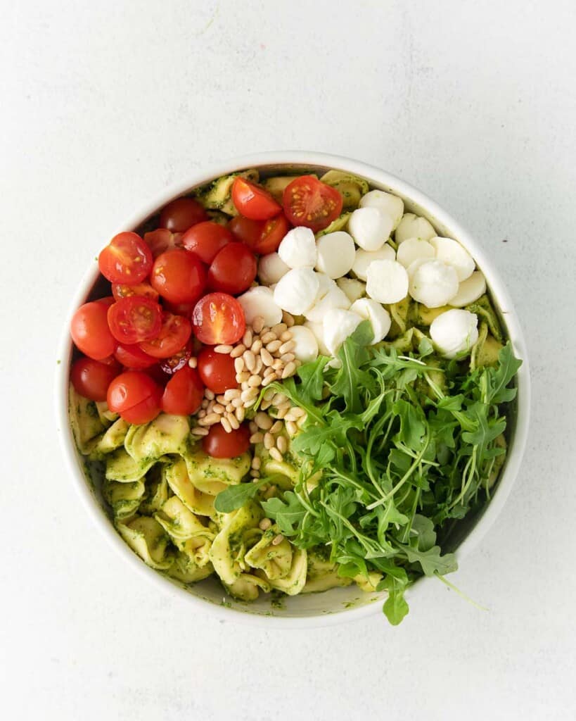 Italian caprese tortellini pasta salad ingredients in a bowl.