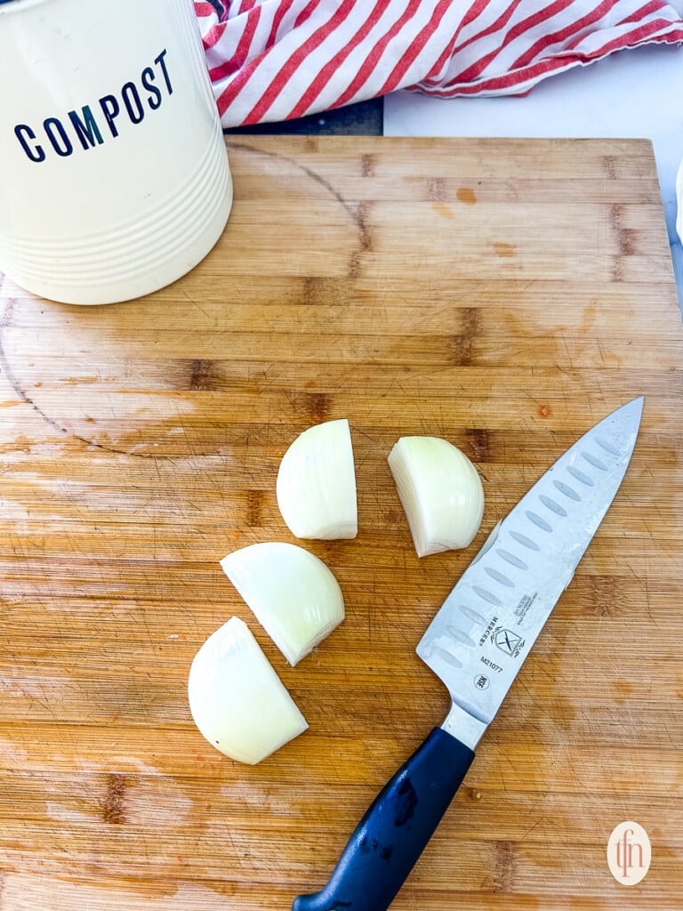 Chopped onion on a cutting board next to a chef's knife.