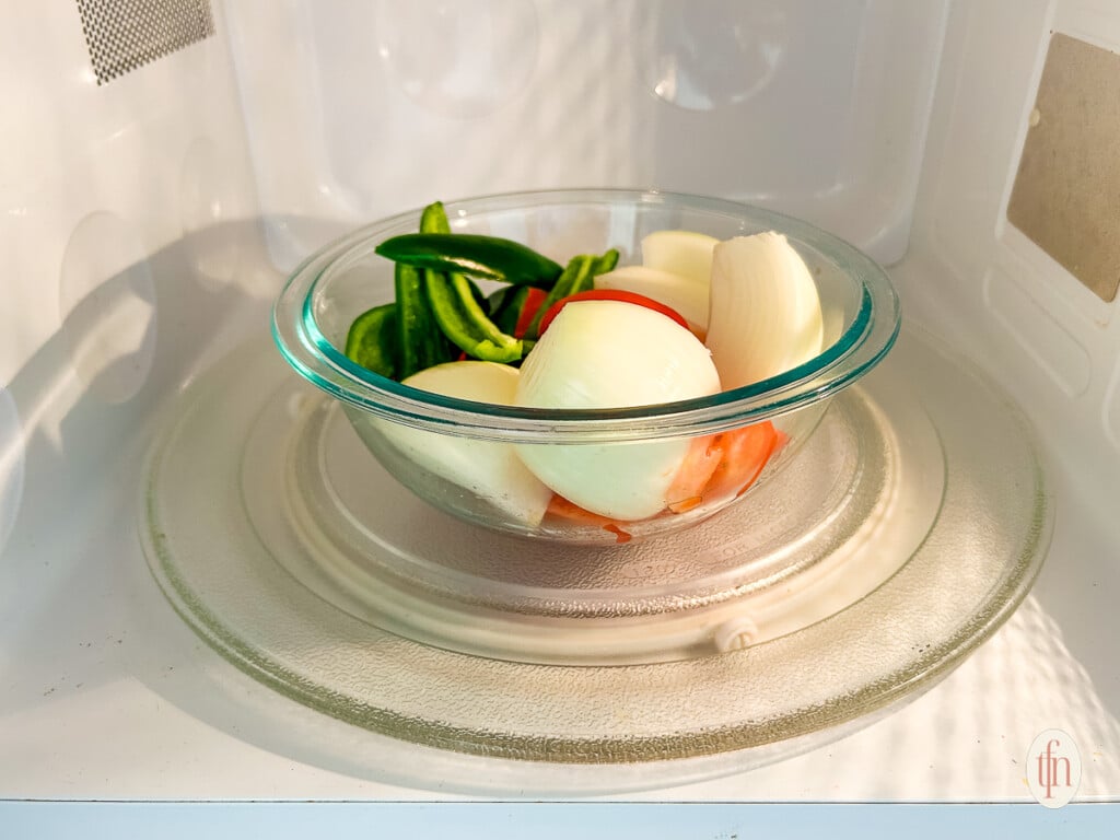 Microwaving vegetables in a clear glass bowl for food processor salsa.