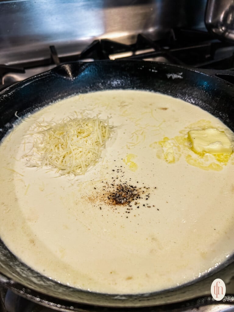 Making alfredo sauce in a skillet on a stove top.
