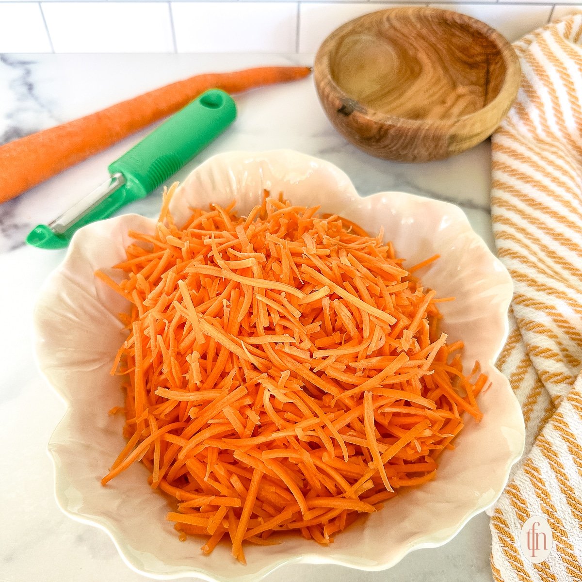 Shredded carrots in a small white bowl.