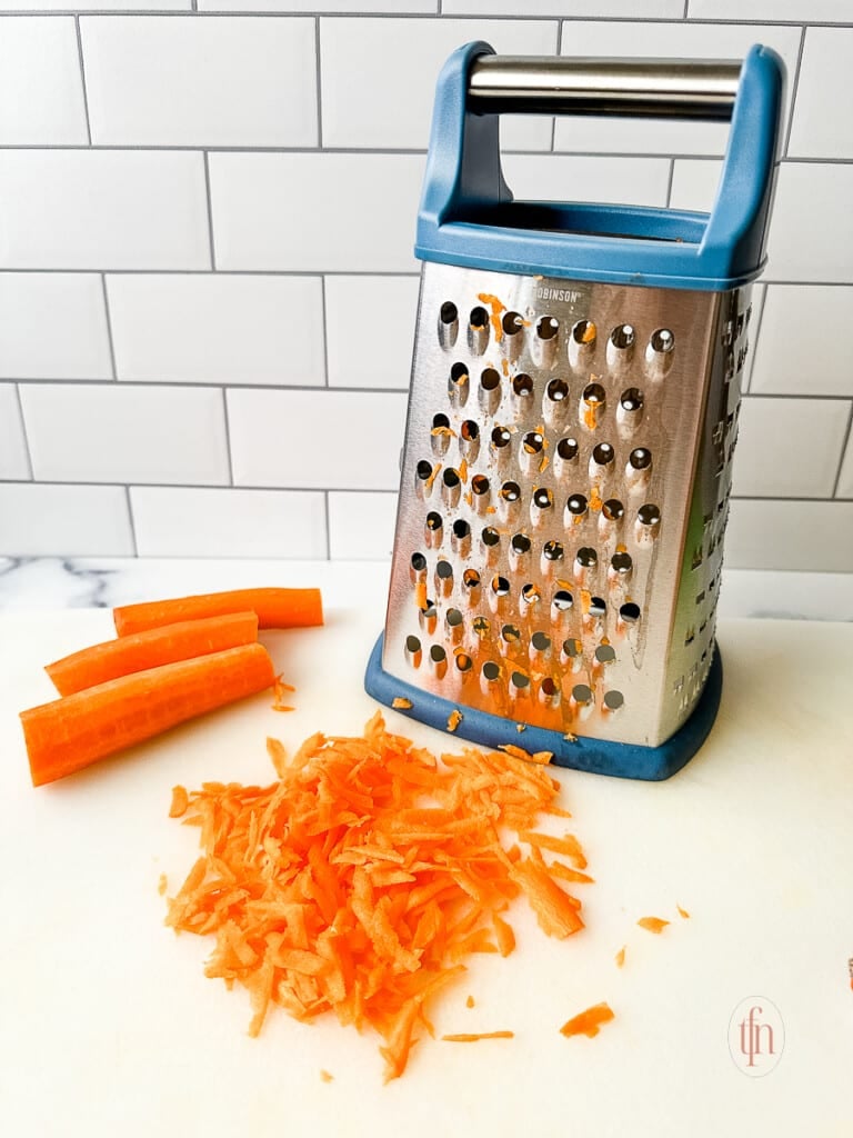 Shredding carrots on a box grater.