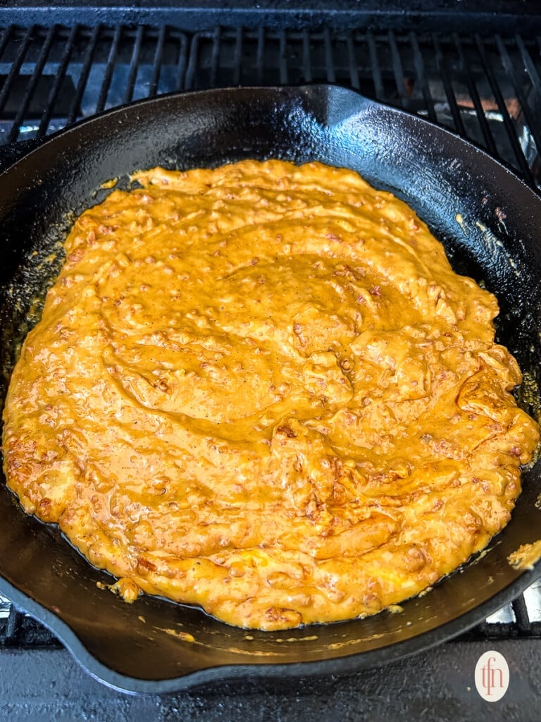 Creamy melted cheese in cast iron pan.