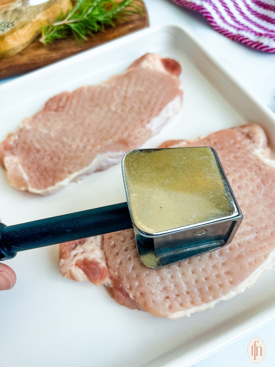 Woman showing how to tenderize pork chops with a tenderizing mallet.