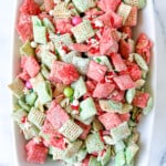 Sweet snack mix with red and green coated cereal in a white serving bowl.